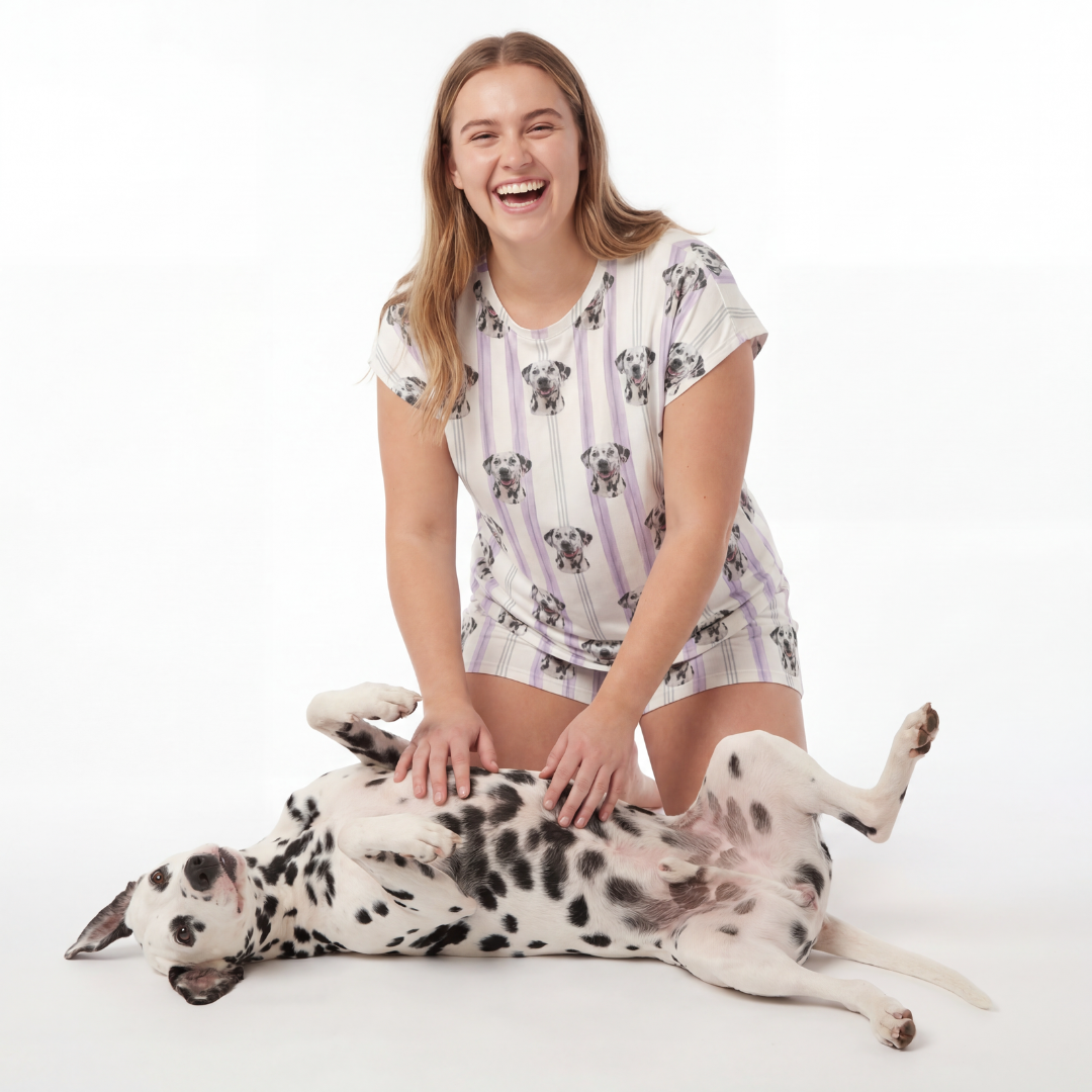 Woman in a pajama set sitting next to a Dalmatian dog on a white background