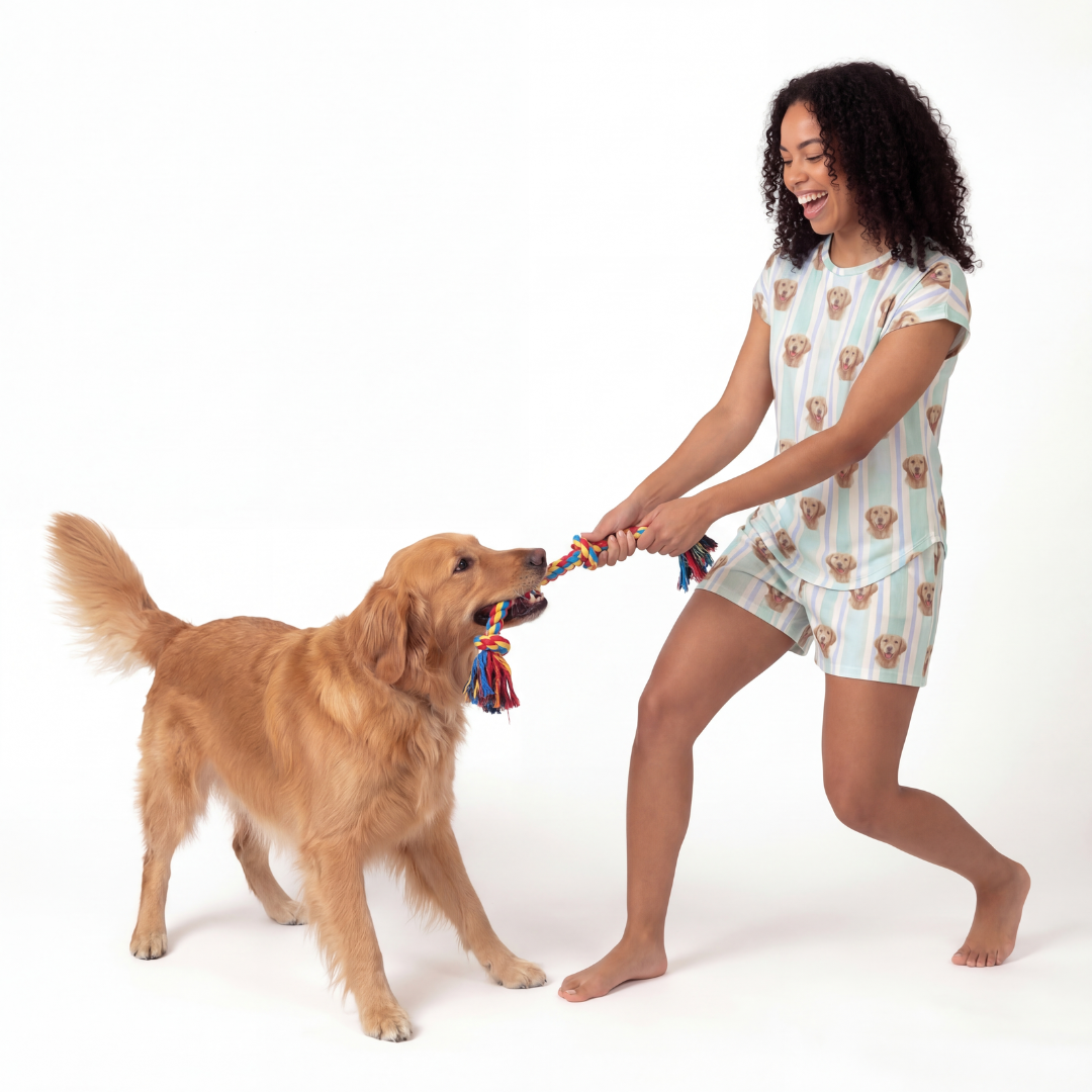 Woman in pajama set playing tug with a dog on a white background