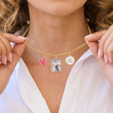 Gold charm necklace with a pendant featuring a dog's photo and name 'Sally', held by a person wearing a white shirt.