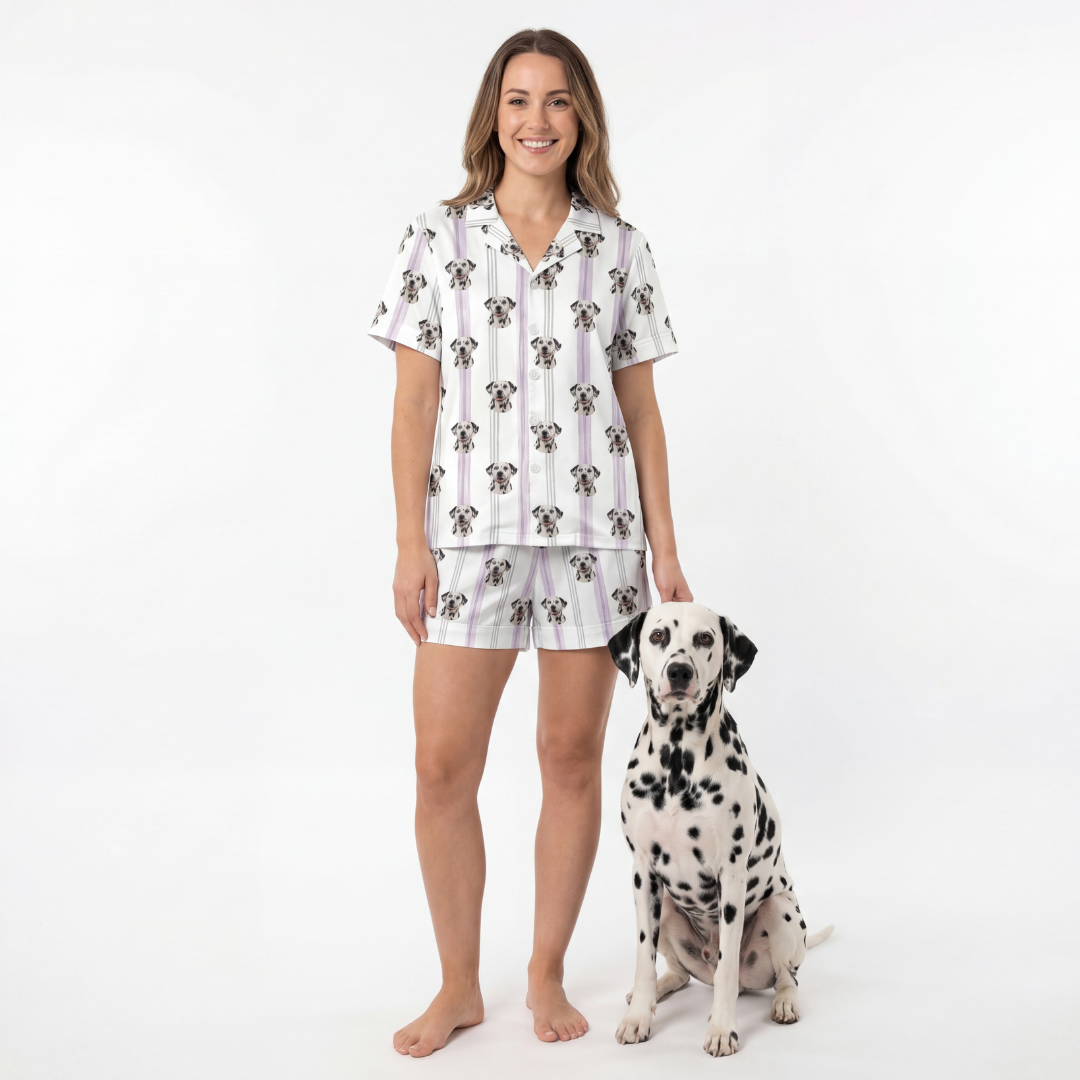 Woman wearing a short button down pajama set standing next to a Dalmatian dog on a white background[LilacStripes]