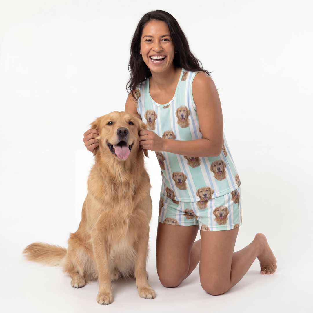 Woman in a dog-themed tank top pajamas kneeling next to a golden dog on a white background