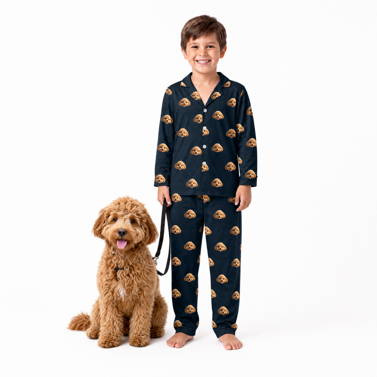 Child wearing black pajamas with dog pattern standing next to a brown dog on a white background