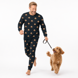 Man wearing a black dog-print pajama set walking a small tan dog on a leash.