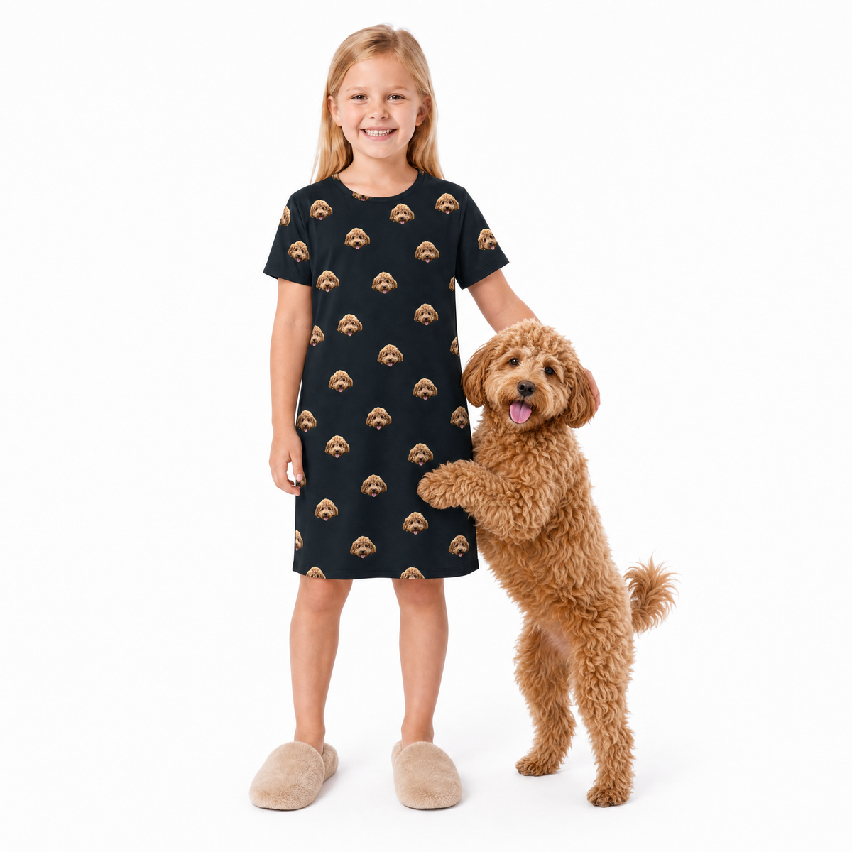 Girl wearing a black dress with dog pattern standing next to a brown dog on a white background