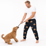 Man wearing navy jogger pants with dog pattern playing tug-of-war with a dog on a white background
