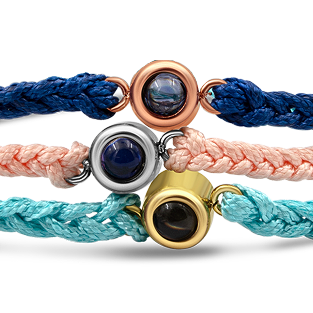 Close up of braided bracelets with a black bead charm in 3 colors.