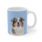 A clean product shot of a blue ceramic mug featuring a smiling, multicolored Australian Shepherd [SkyBlueImageCutOut]