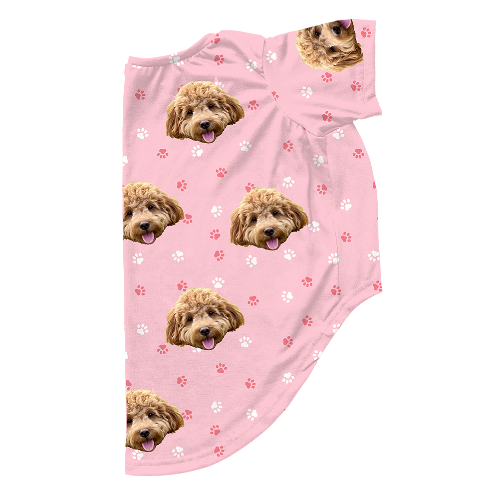 Light pink dog pajama with repeating pet faces on them