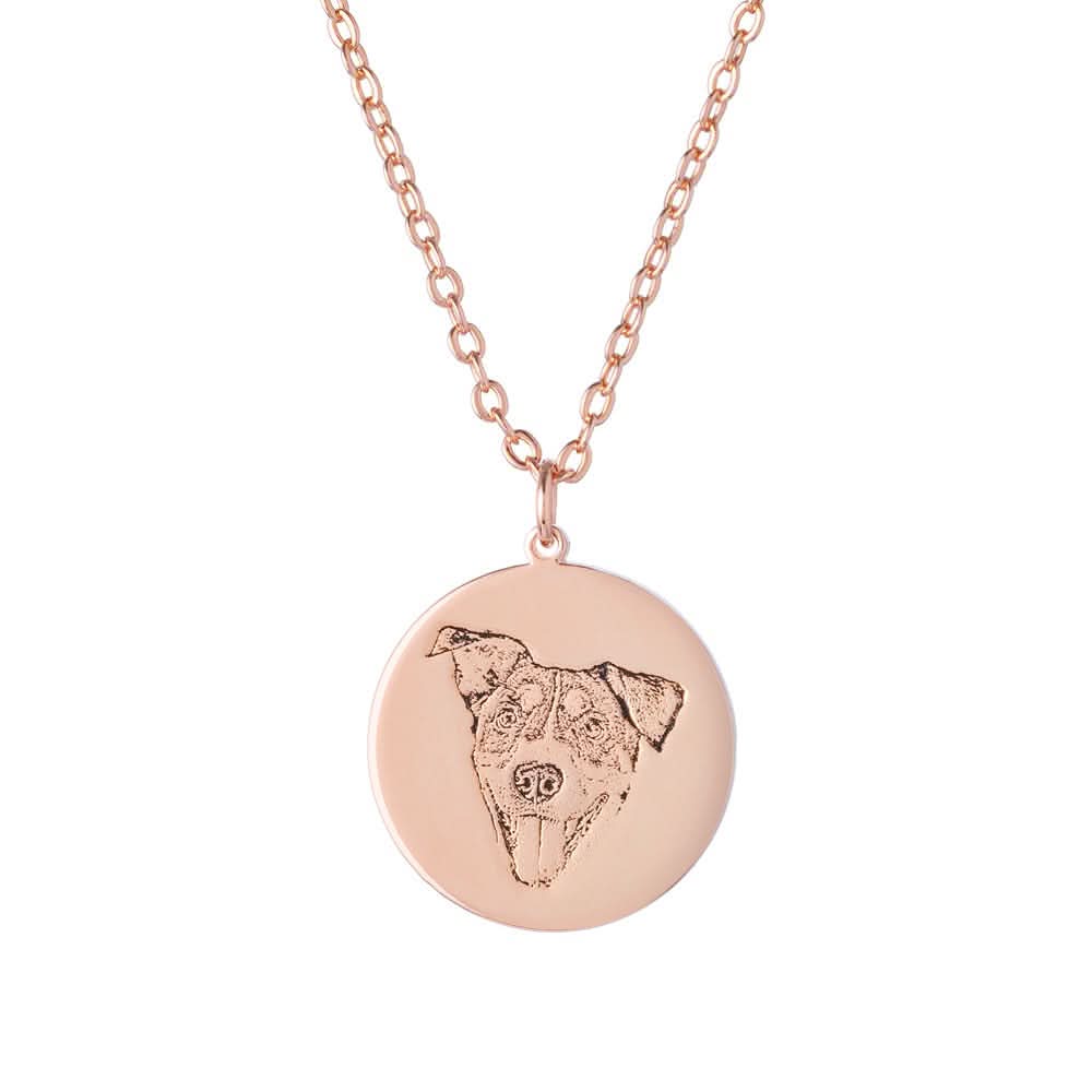 Rose gold dog-portrait necklace with a blue gemstone detail on the pendant.