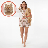 A woman modeling a matching cat-print pajama set while holding an orange tabby cat, with circular inset close-ups showing the cat face printed on the pajama top and shorts. Shot on a clean white studio background.