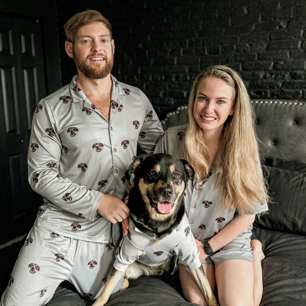 Man and woman in matching pajamas with a dog on a couch.
