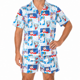 A man wearing a matching short-sleeve button-up pajama shirt and shorts set with a colorful cartoon dog print on a white background.
