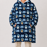 A person wearing a navy hooded sweatshirt with an allover 'Frosty Snowman' cartoon print, paired with light beige pants, against a plain light gray studio background.