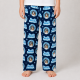 A person wearing navy blue fleece pants with a repeating 'Frosted Snowman' dog print, standing barefoot against a light gray studio background.