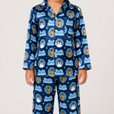 A child wearing a navy blue long-sleeve pajama set with a repeating 'Frosty Snowman' dog print, photographed against a plain light gray studio background.