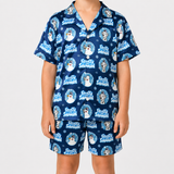 A child wearing a matching navy blue pajama set with a repeating 'Frozen Wonderland' print featuring Snow White, Dalmatian dogs, and snowflakes, shown against a light gray studio background.