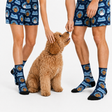 A person and a dog wearing matching navy blue socks and shorts with a 'Freshly Squeezed' cartoon bear pattern, shown on a clean white studio background.
