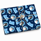 A wrapped rectangular gift box on a white background, covered in dark blue wrapping paper with repeated Frosty the Snowman illustrations and text, tied with natural twine in a bow.