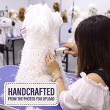 A woman grooming a fluffy white dog with an electric clipper in a grooming salon. A purple tag is attached to the dog, and a 'HANDCRAFTED FROM THE PHOTOS YOU UPLOAD' graphic overlay is in the bottom left corner.