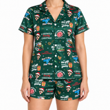 A model wearing a matching two-piece pajama set with a dark green Christmas-themed print featuring the text 'A Griswold Christmas', Santa hats, gift boxes, and holiday illustrations.