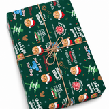 A rectangular gift box wrapped in dark green Christmas-themed wrapping paper with a brown twine bow, photographed on a clean white background. The paper features repeated illustrations of a blue dog in a Santa hat, the words 'A Griswold Christmas,' holiday trees, ornaments, and small red and white motifs.