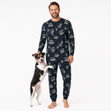 Man wearing a I love dad pajama set with 'I love dad' text and dog illustrations, standing next to a dog on a white background.