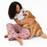 Woman in pink pajama pants with dog pattern sitting on the floor with a golden retriever.