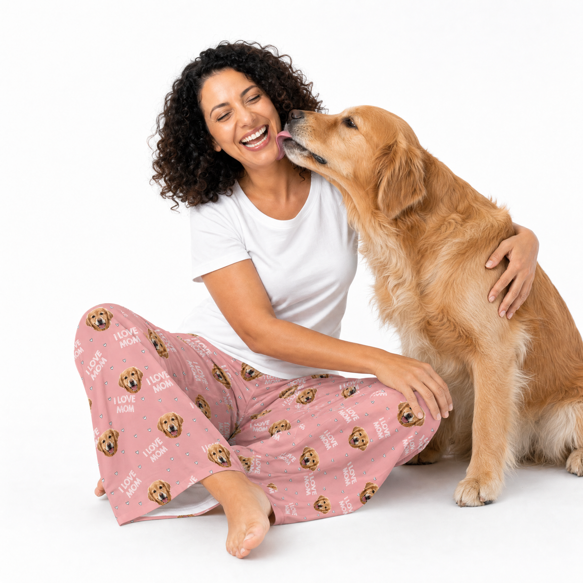 Woman in pink pajama pants with dog pattern sitting on the floor with a golden retriever.