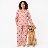 Woman wearing pink pajamas with dog patterns standing next to a golden retriever on a white background