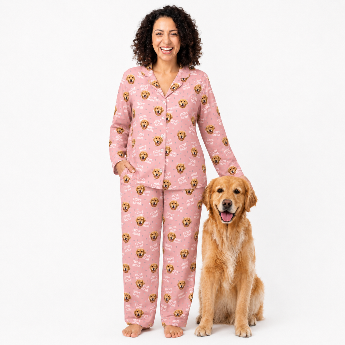 Woman wearing pink pajamas with dog patterns standing next to a golden retriever on a white background
