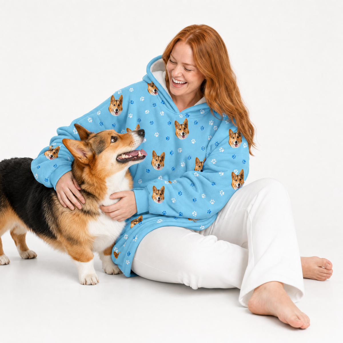 Light blue paws fleece blanket hoodie theme – person in corgi-print hoodie cuddling corgi dog.