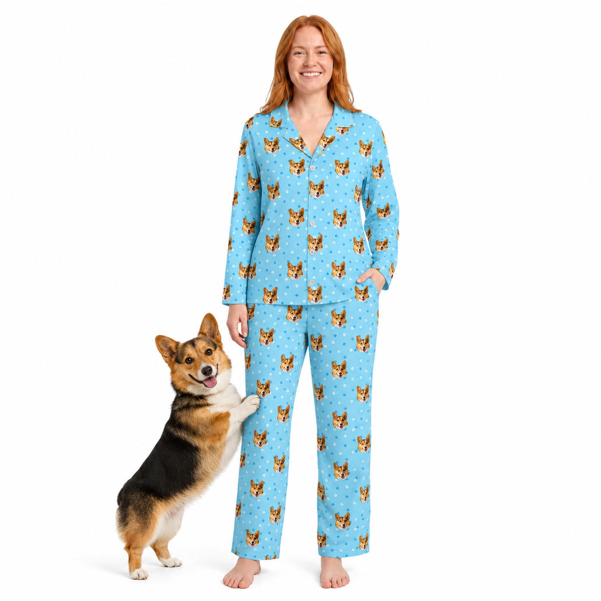 Woman wearing a light blue paws pajama set with dog pattern standing next to a dog on a white background
