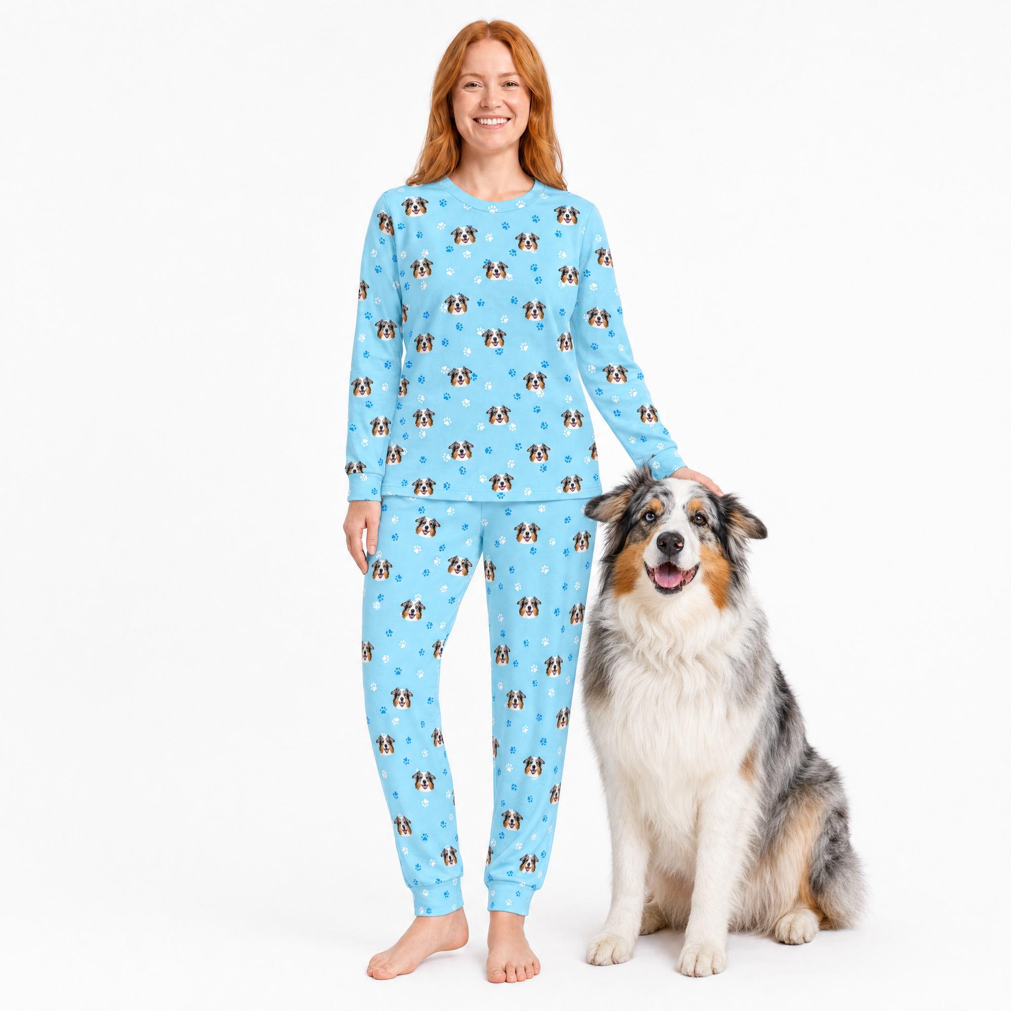 Woman wearing a blue jogger pajama set with dog pattern, sitting next to a dog on a white background