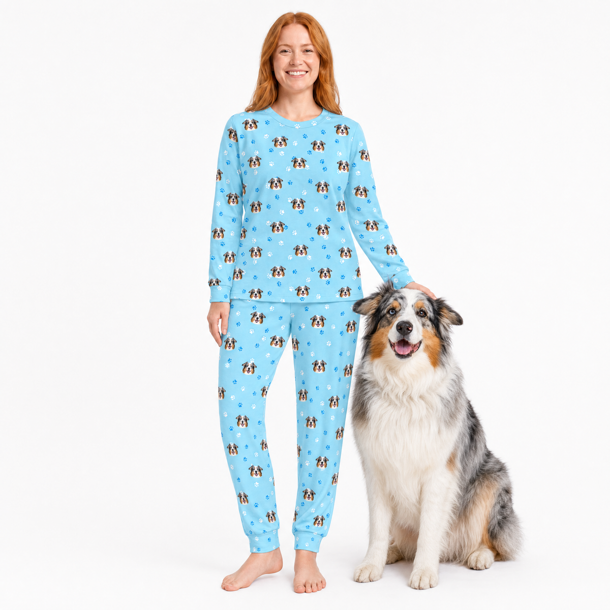 Woman wearing a blue jogger pajama set with dog pattern, sitting next to a dog on a white background