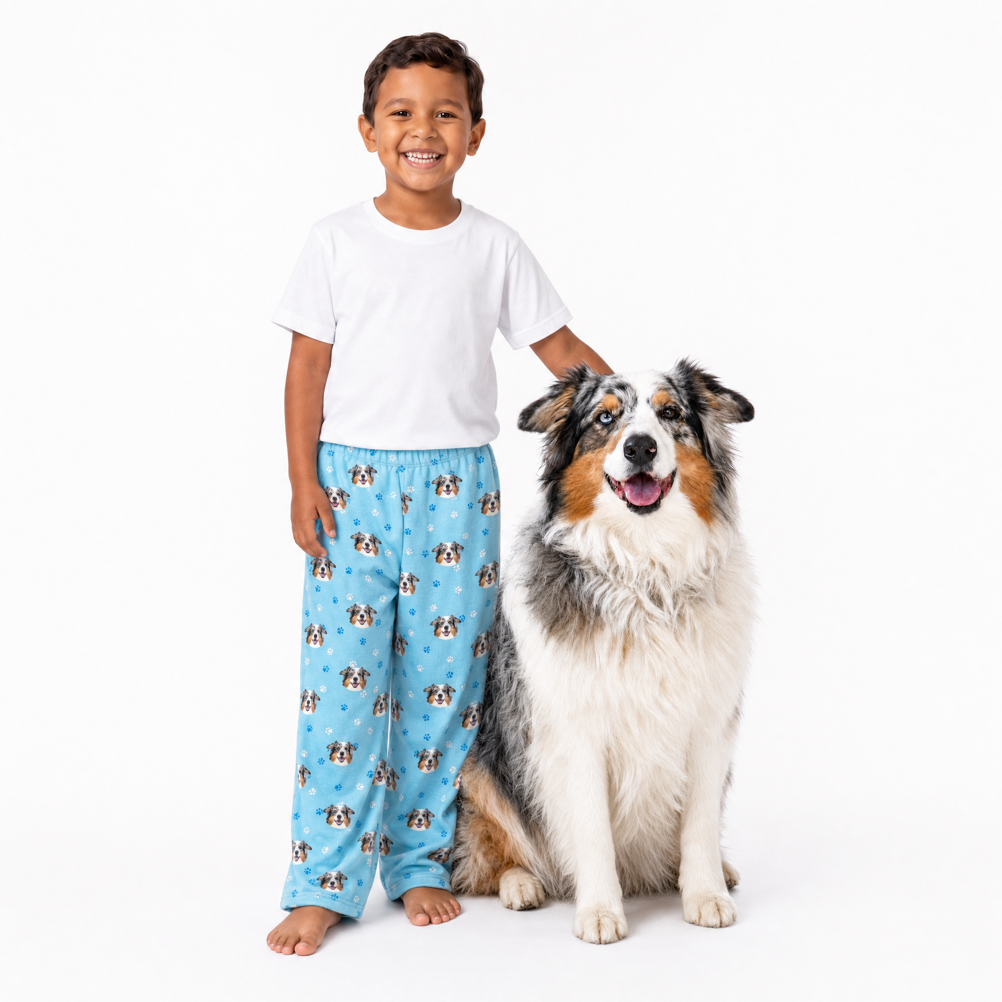 Child wearing Light Blue pajama pants with dog pattern and a dog sitting next to them on a white background