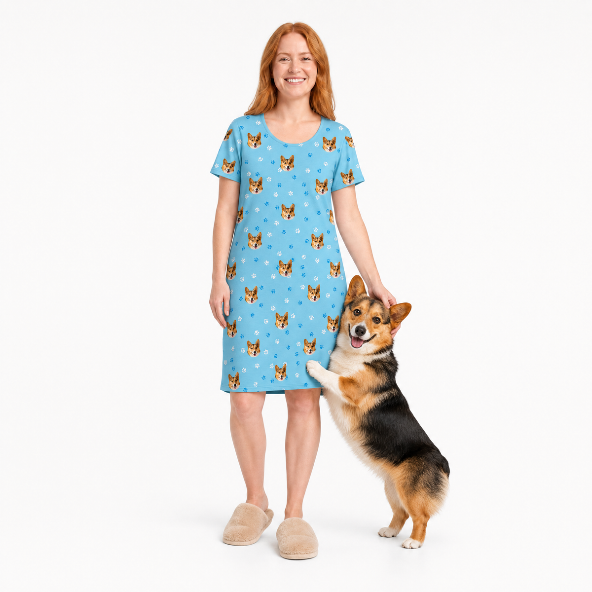 Woman wearing a light blue nightgown with dog pattern holding a corgi on a white background