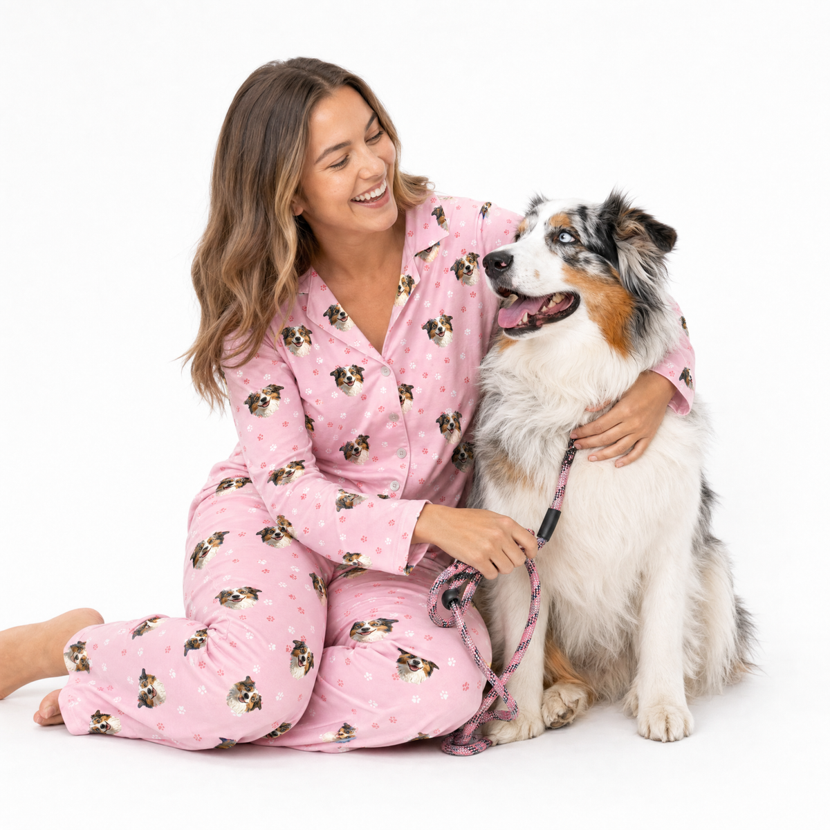 Woman in pink pajamas with a dog on a white background