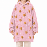 Pink blanket hoodie with cat pattern worn by a person on a white background