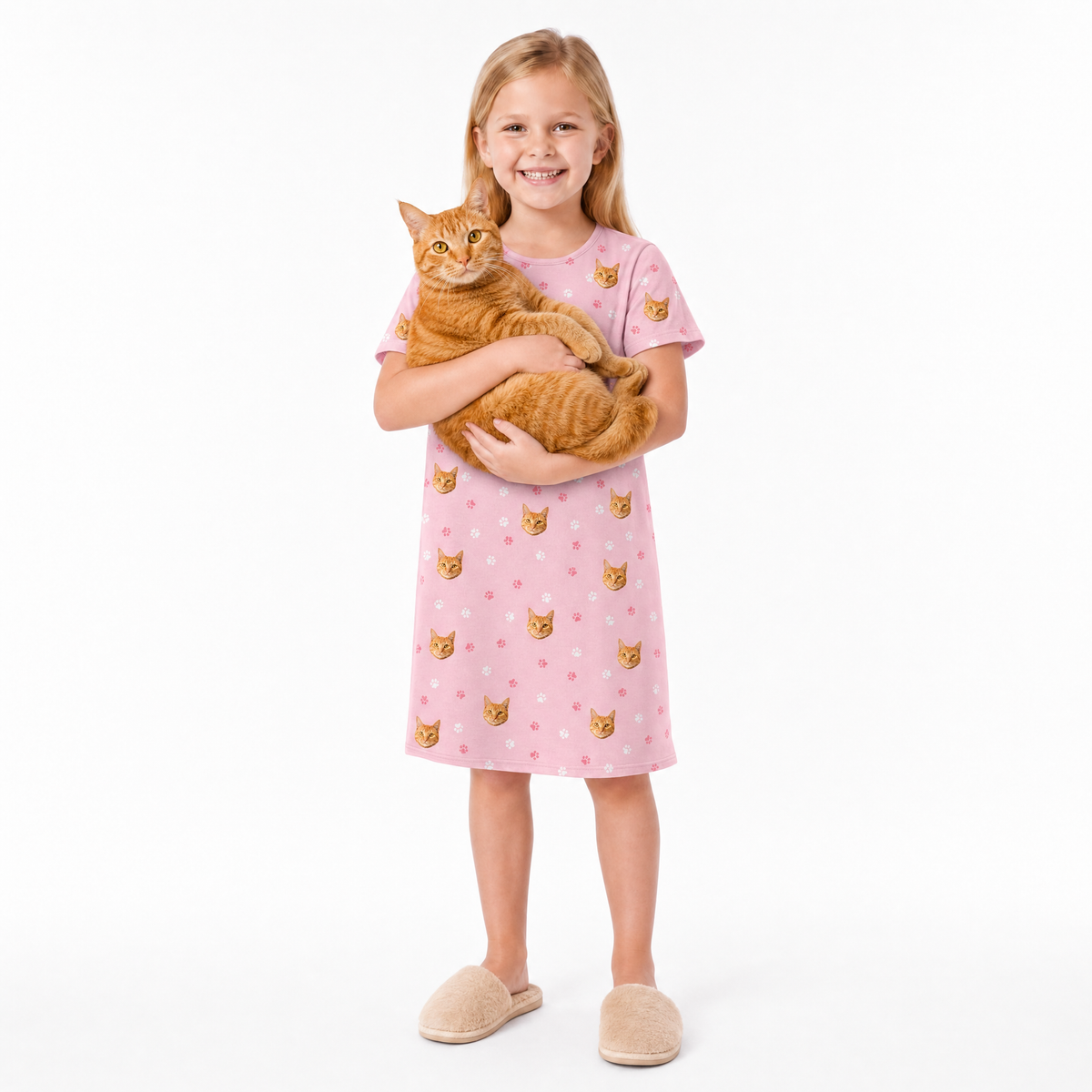 Girl in a pink nightgown with cat pattern holding an orange cat on a white background