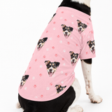 Dog wearing a light pink custom dog shirt with paw prints and a repeating dog face pattern.