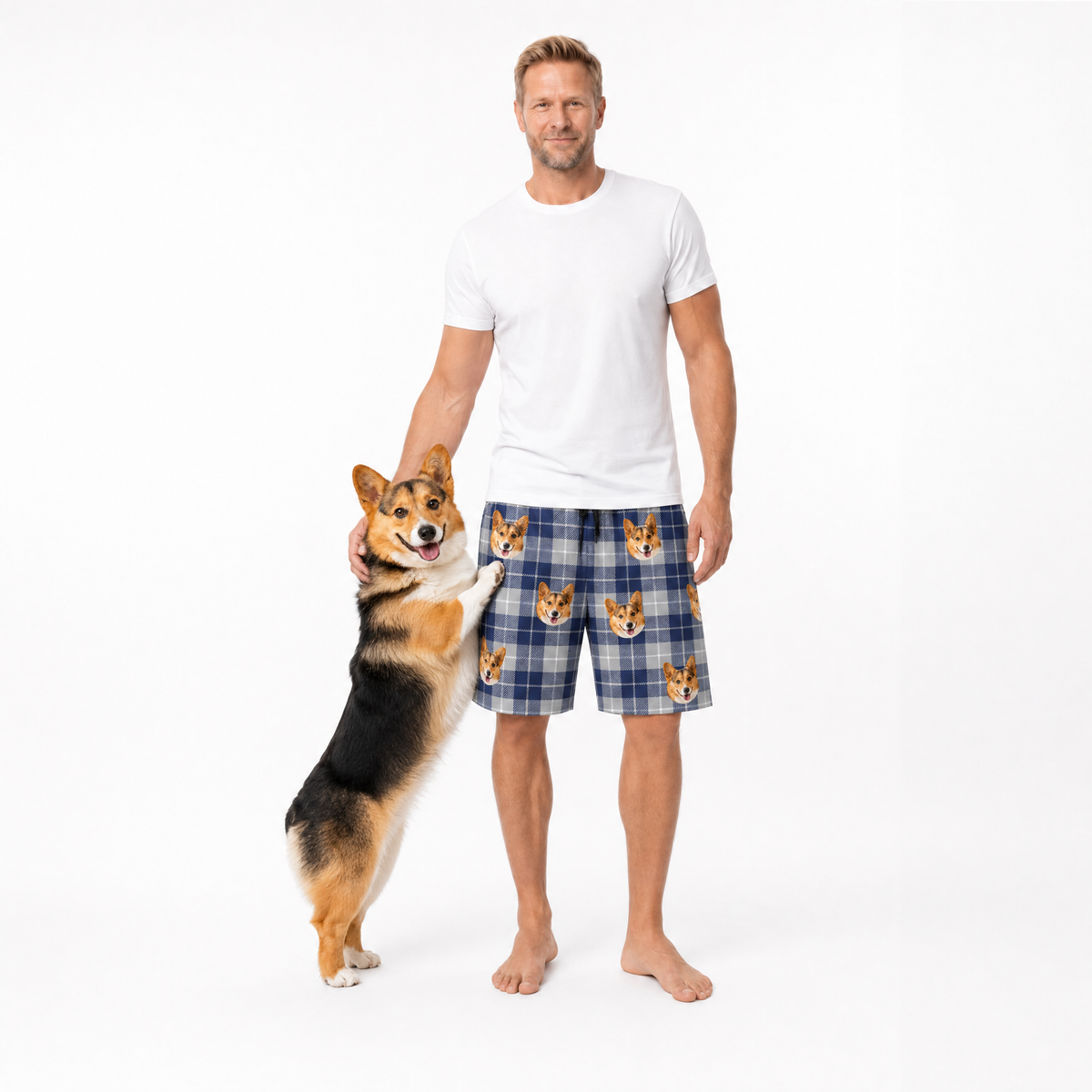Man wearing a blue plaid shorts with dog pattern holding a corgi dog on a white background