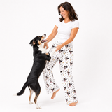 Paws and bones theme – person in dog-print pajamas playing with black, white, and tan dog.