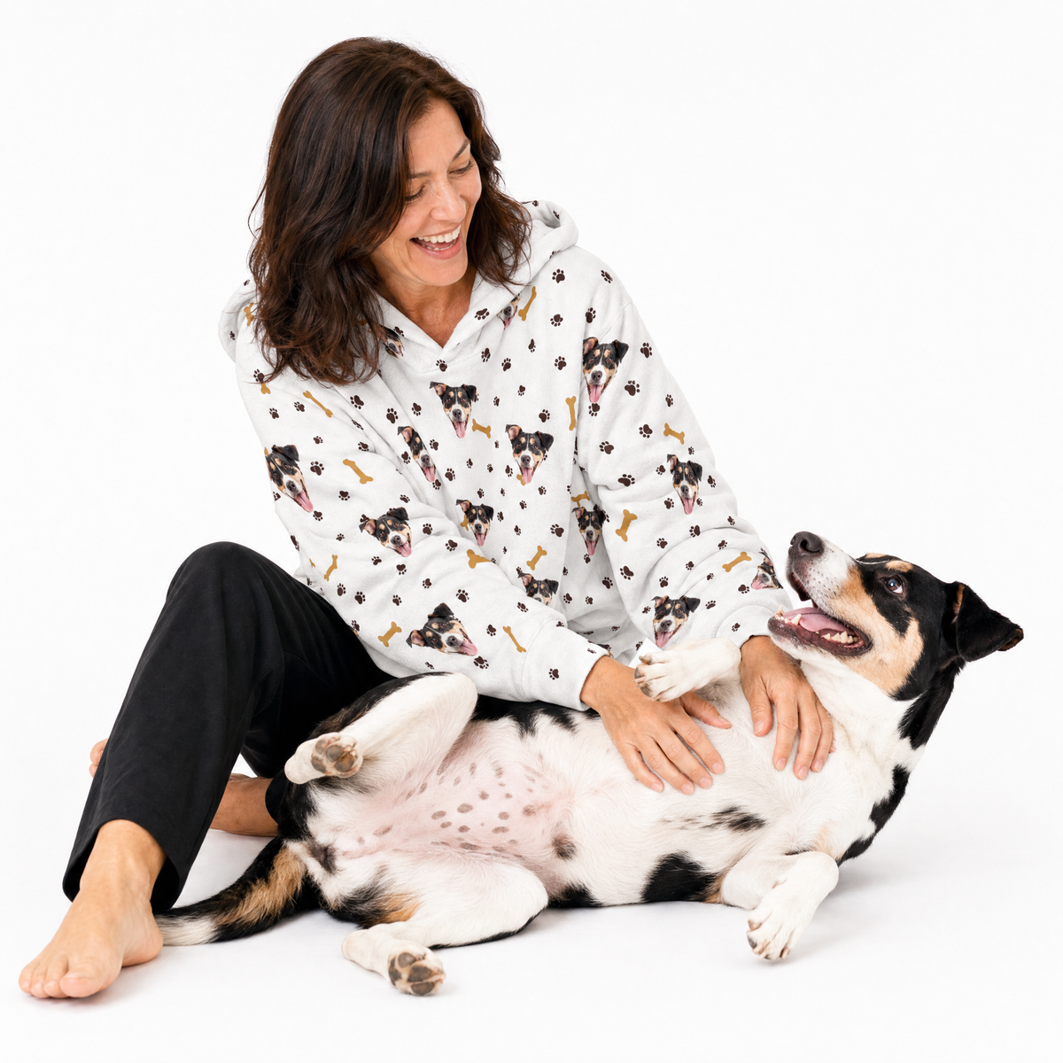 Paws and bones hoodie theme – person in dog-print hoodie playing with black, white, and tan dog.