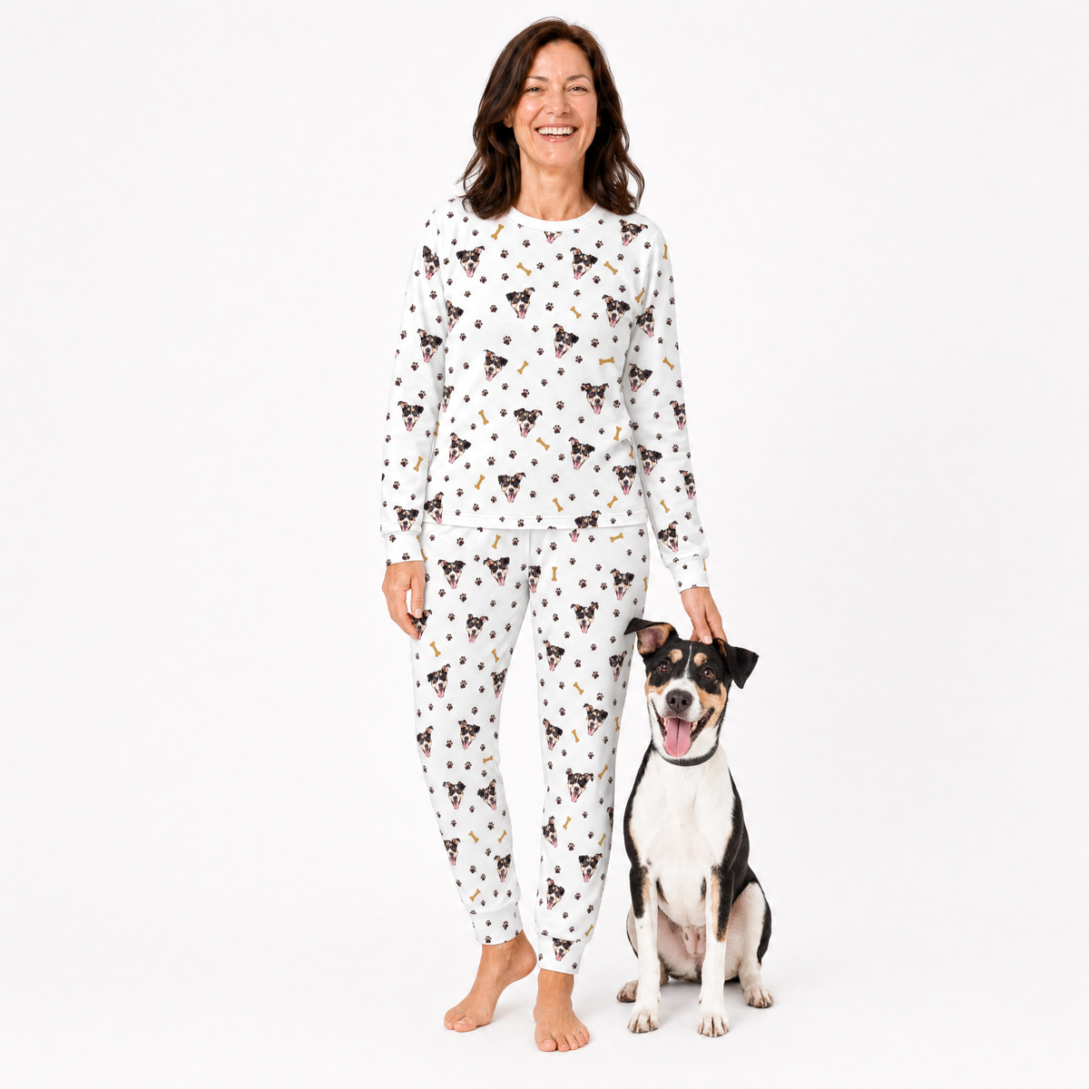 Woman wearing a white patterned jogger pajama set standing next to a dog on a white background
