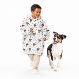 Paws and bones kids fleece blanket hoodie theme – child in dog-print hoodie walking with black-and-white dog.