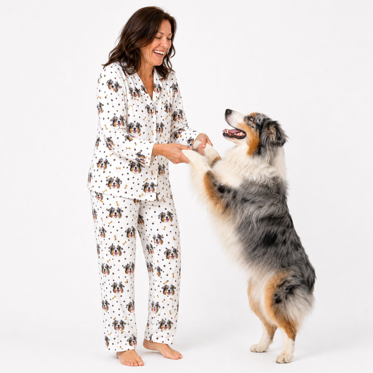 Woman in dog-themed pajamas interacting with a dog on a white background