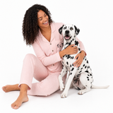 Woman in pink pajamas sitting with a Dalmatian dog on a white background