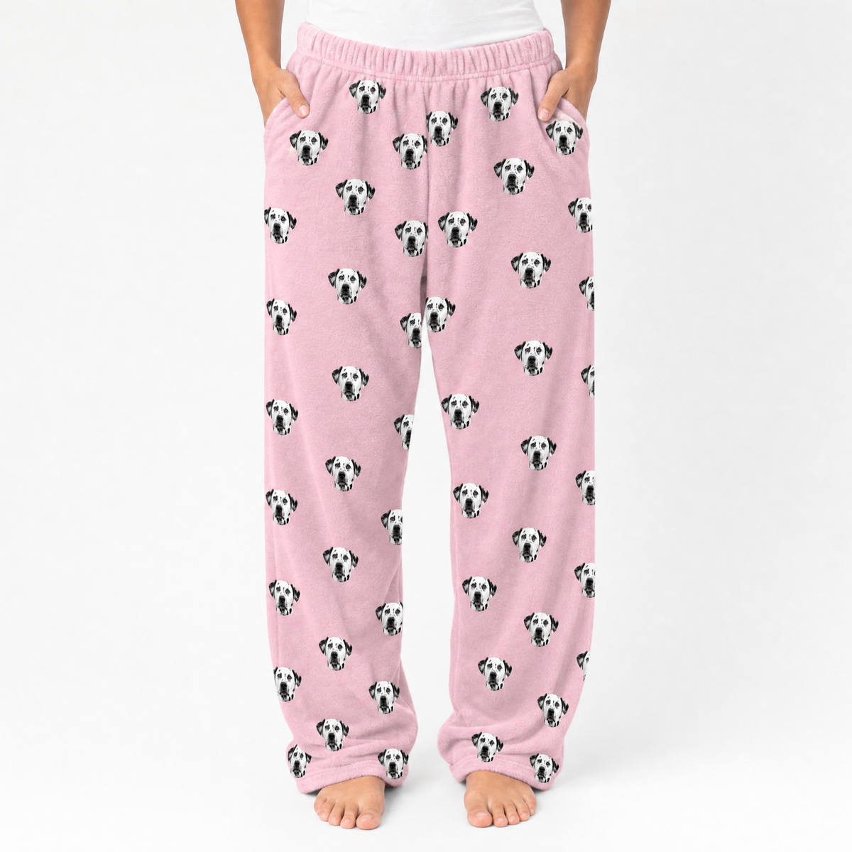 Pink pajama pants with dalmatian pattern worn by a person on a white background