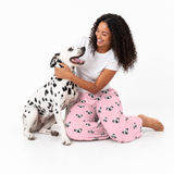 Woman in pink pajama pants with dog pattern sitting on the floor with a Dalmatian dog.