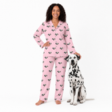 Woman wearing pink pajamas with a Dalmatian dog next to her on a white background